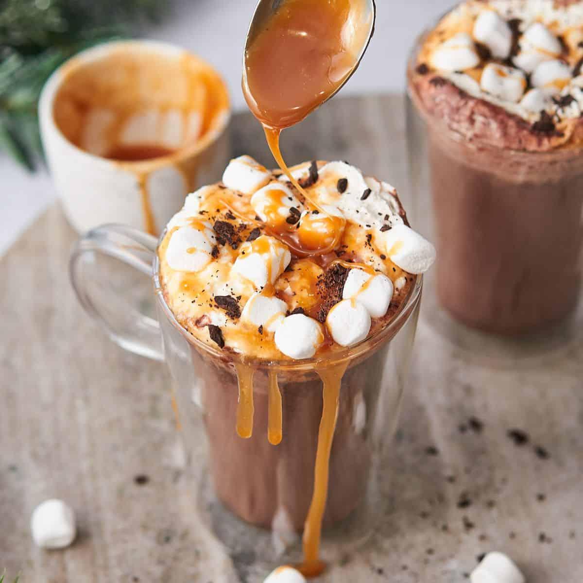 Vibrant close-up of a mug of salted caramel hot chocolate, rich caramel swirl visible, topped with whipped cream and a sprinkle of sea salt