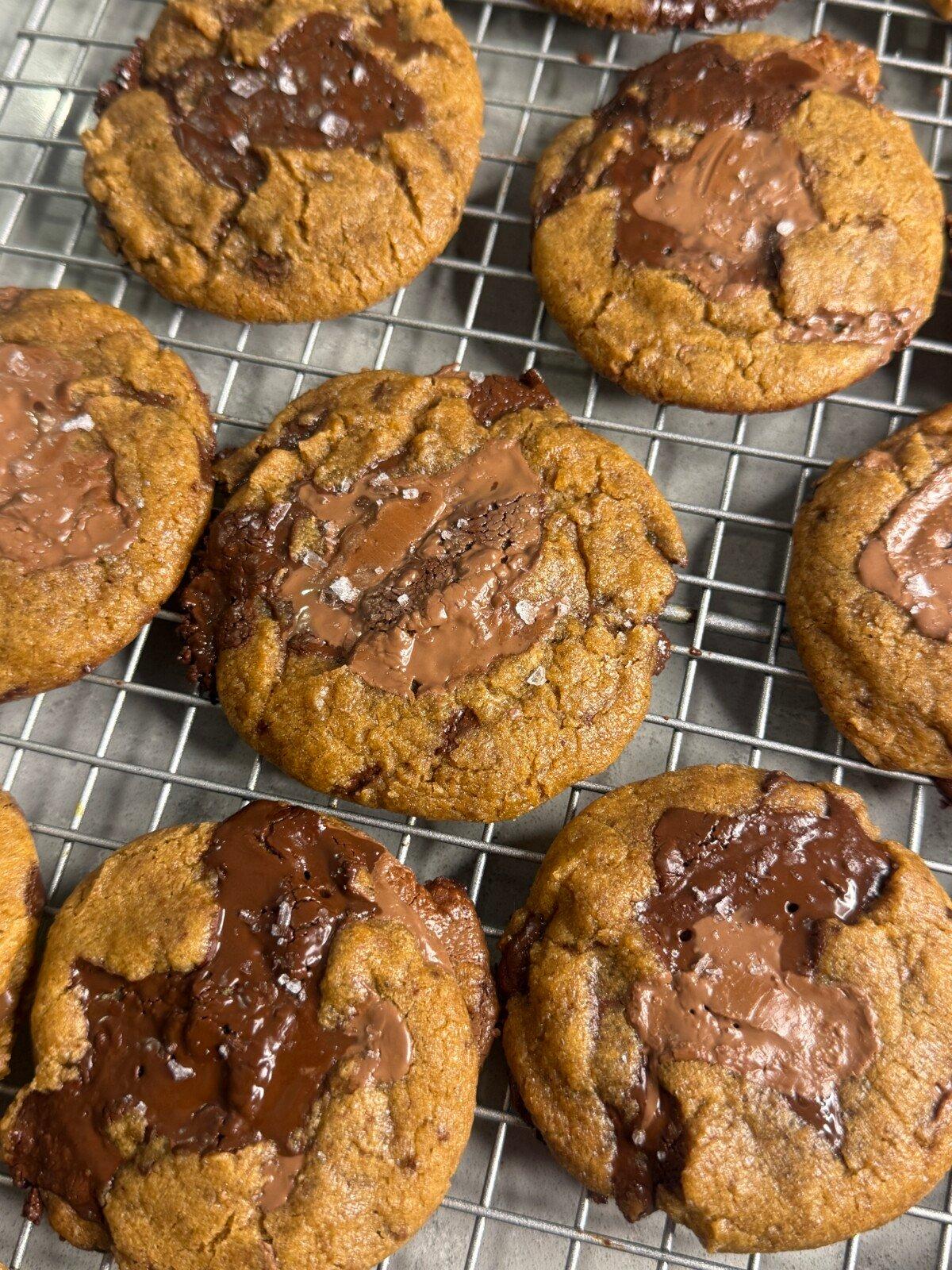 Close-up of a perfectly baked chewy brown butter cookie with crinkled edges on a cooling rack