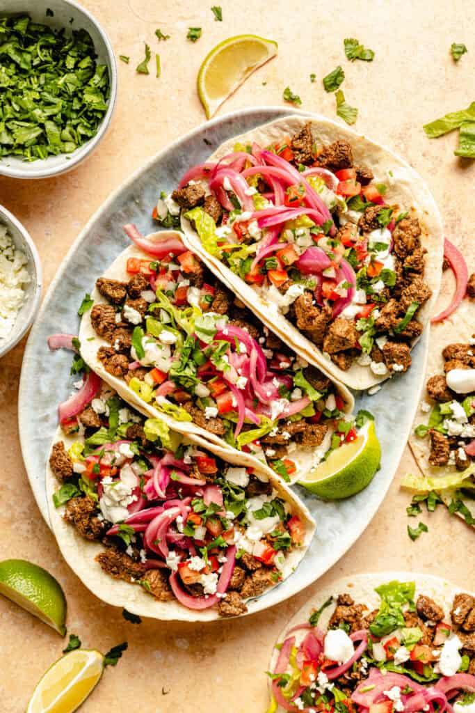a hand assembling a chipotle-lime ground beef taco with various toppings