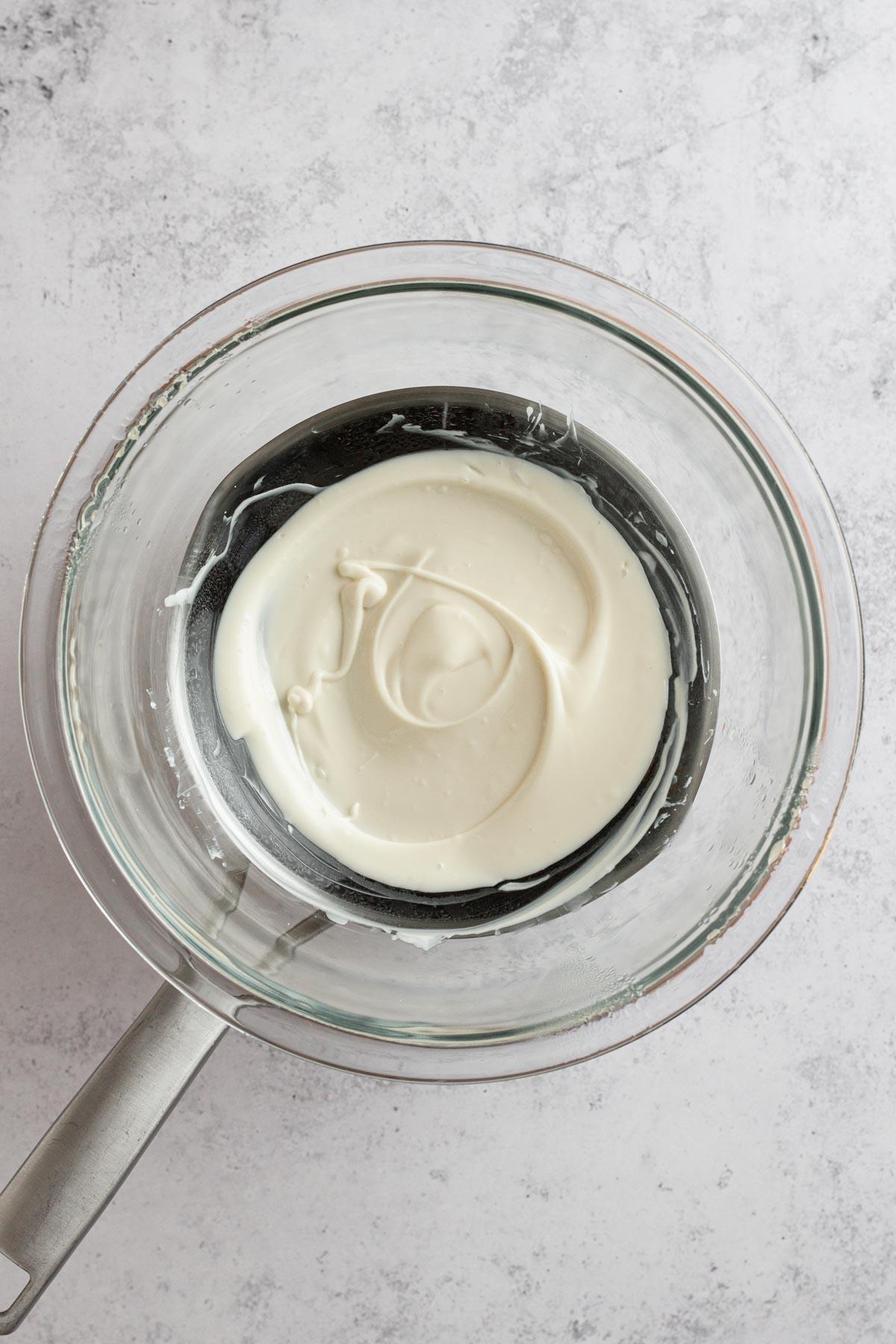Close-up of melted white chocolate being drizzled from a spoon, showing its smooth texture
