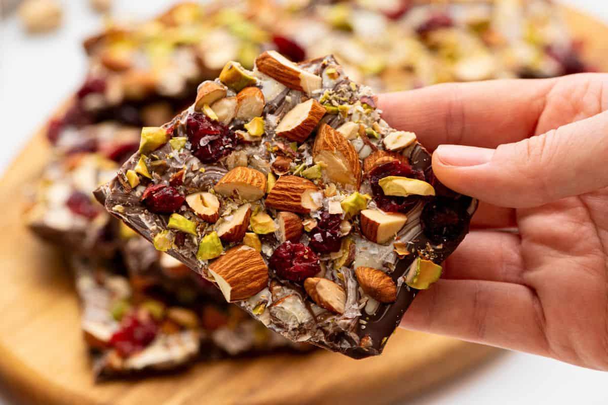 person holding a plate of homemade swirled chocolate bark, smiling with a friend