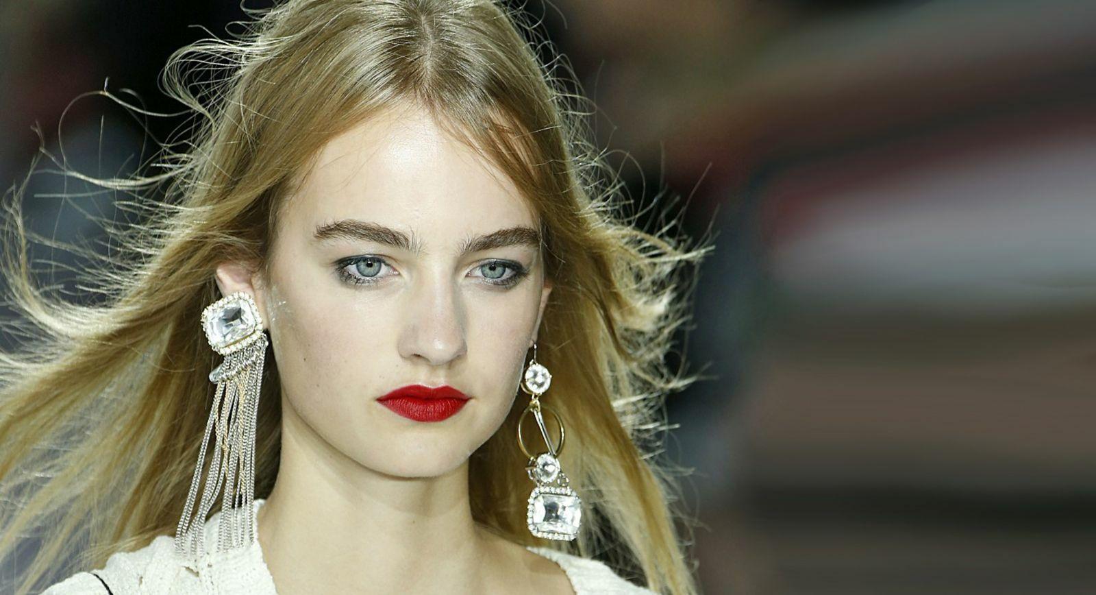 model wearing mismatched earrings