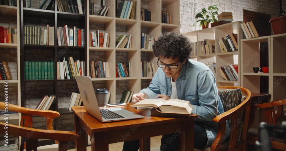 students studying in a library with laptops and books