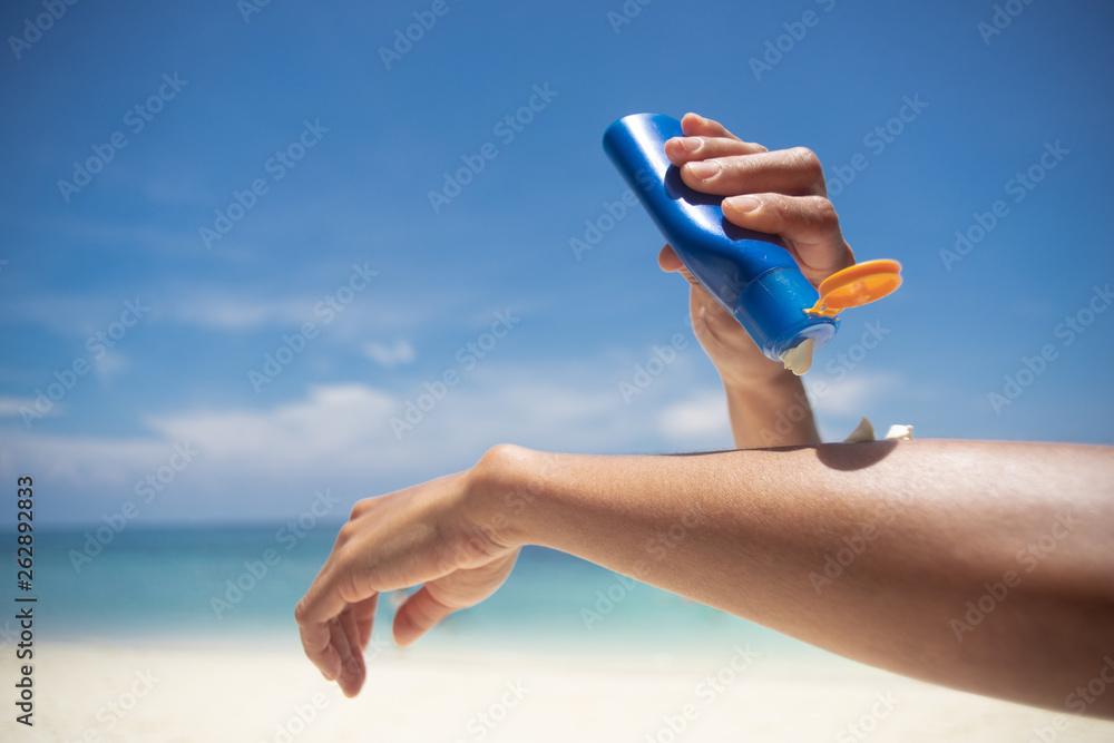 woman applying sunscreen at the beach