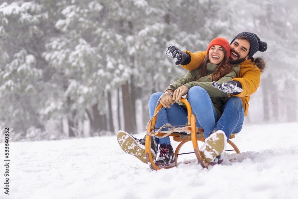 couple sledding down snowy hill