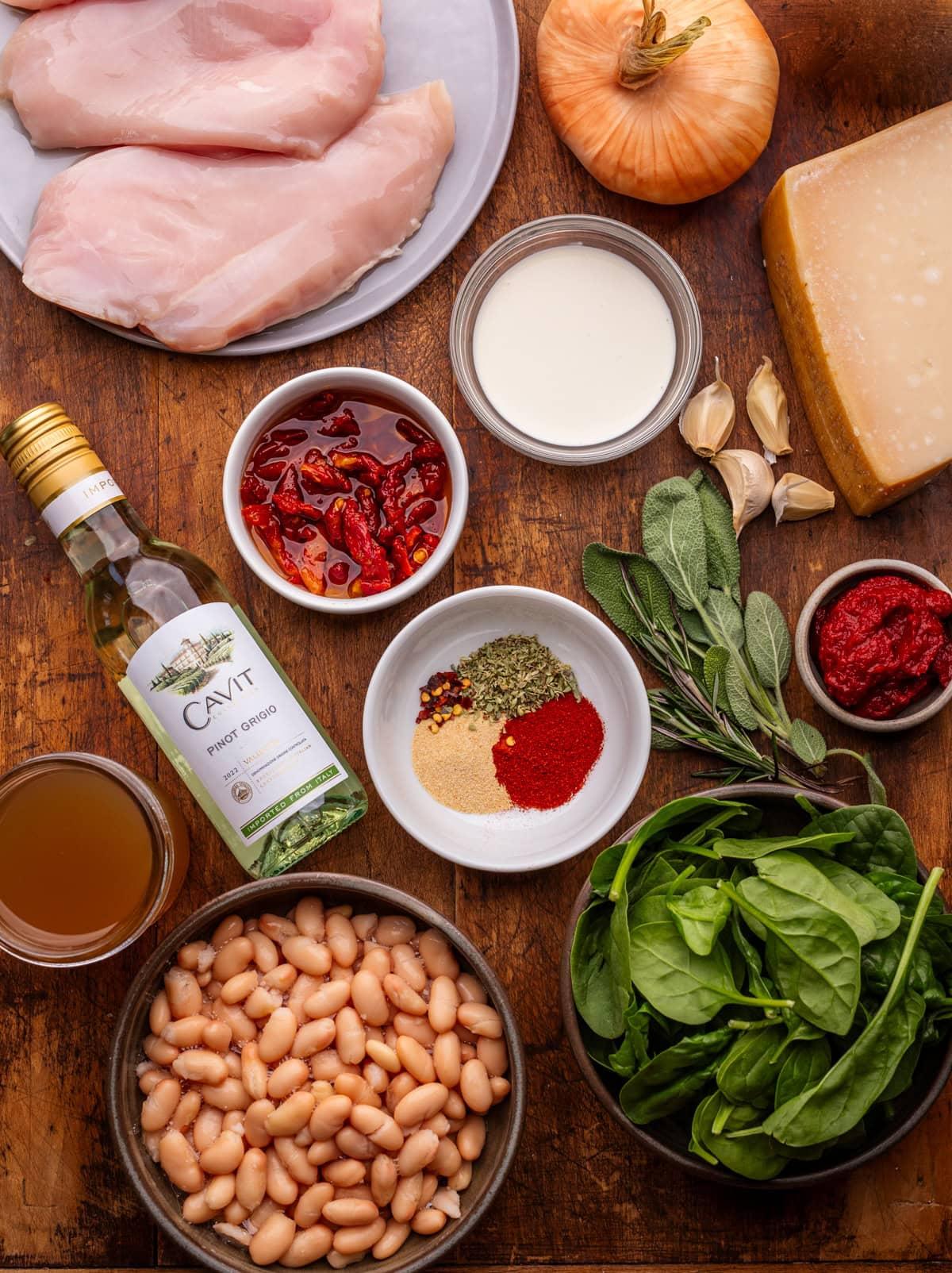 ingredients for creamy tuscan chicken arranged on a wooden board