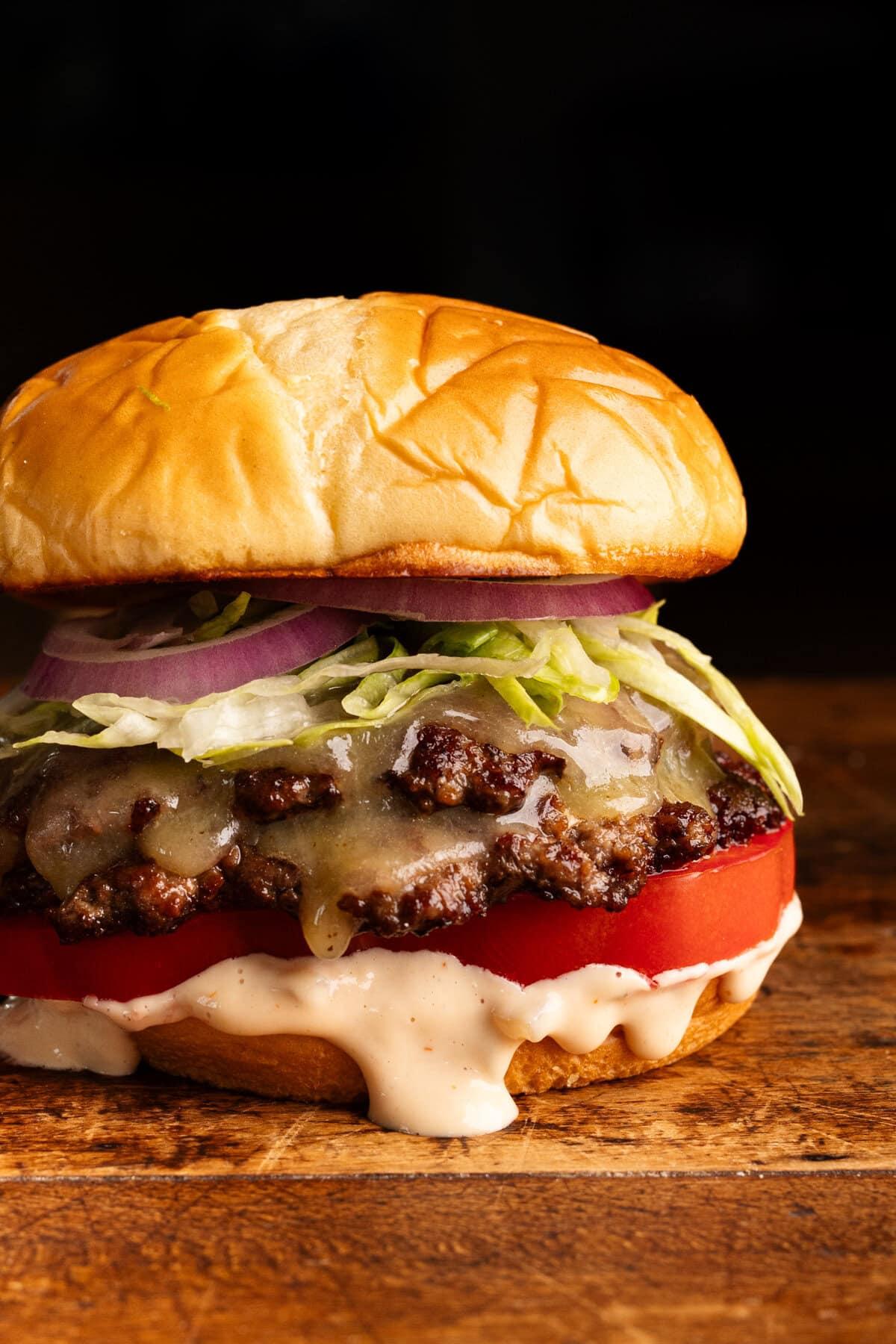 Assembled smash burger on a bun with lettuce, tomato, and sauce