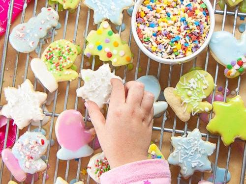 young girl happily decorating sugar cookies with sprinkles