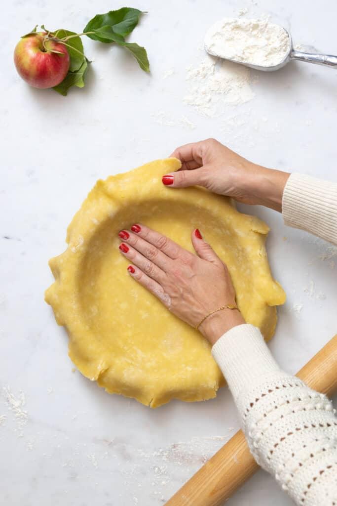 close-up of hands kneading dough for apple pie