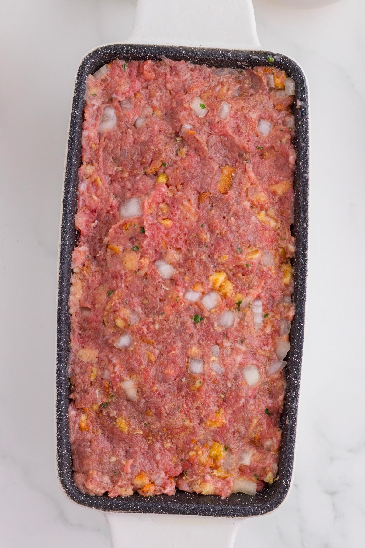 close up shot of uncooked meatloaf in a loaf pan