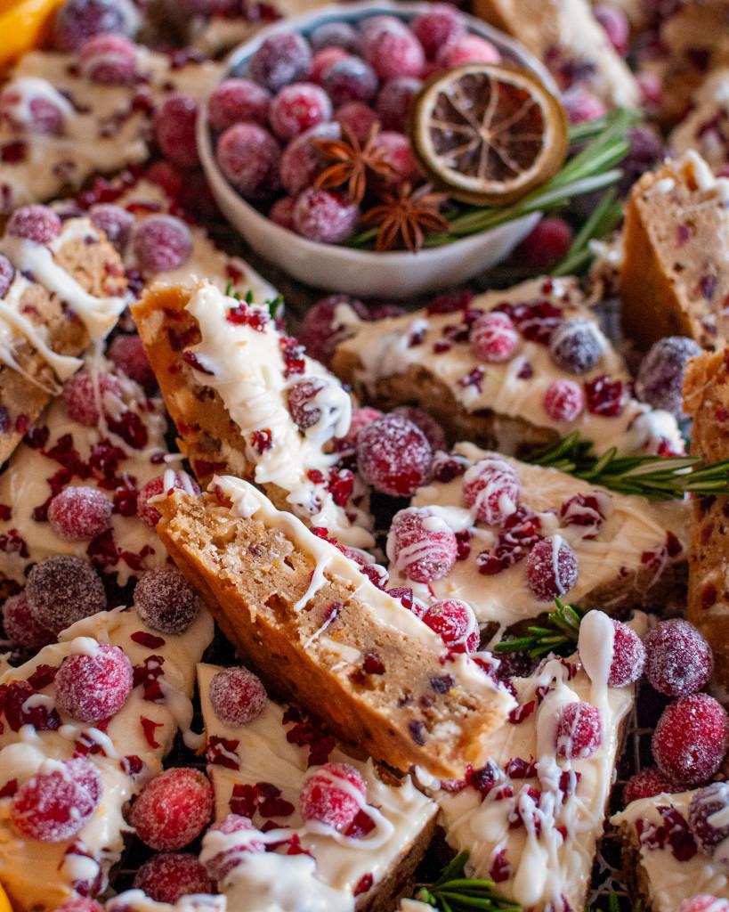 Woman holding a cranberry bliss bar, smiling in a cozy kitchen with soft morning light