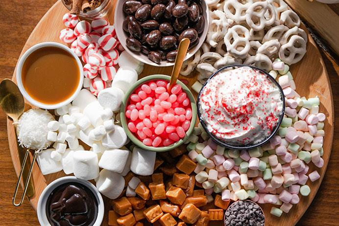 Marshmallow swirl hot chocolate bar setup, with various toppings and steaming mugs