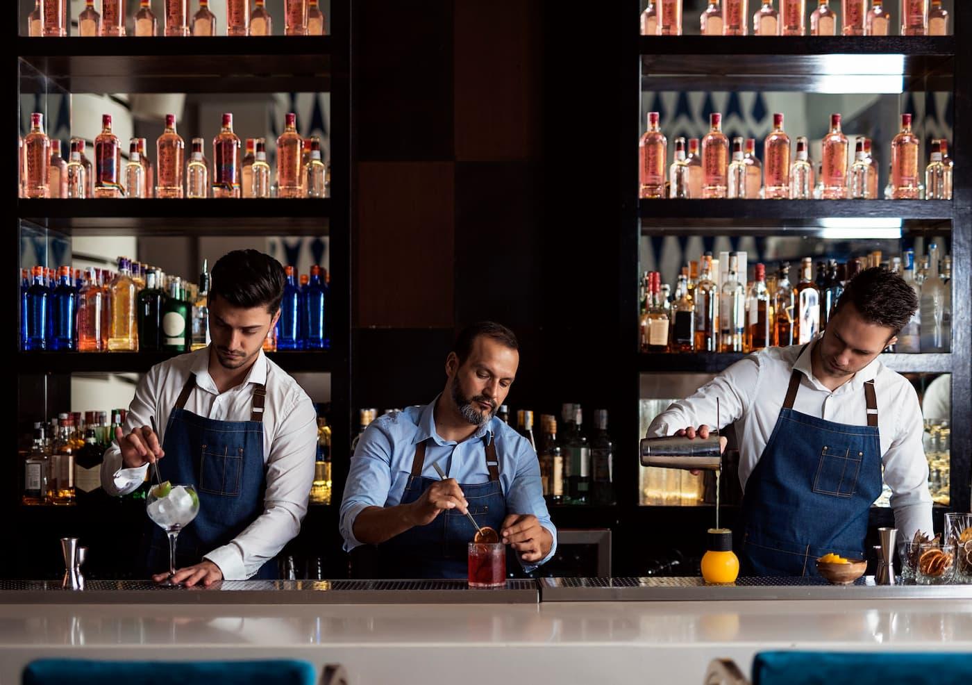 bartender preparing three different cocktails on a bar