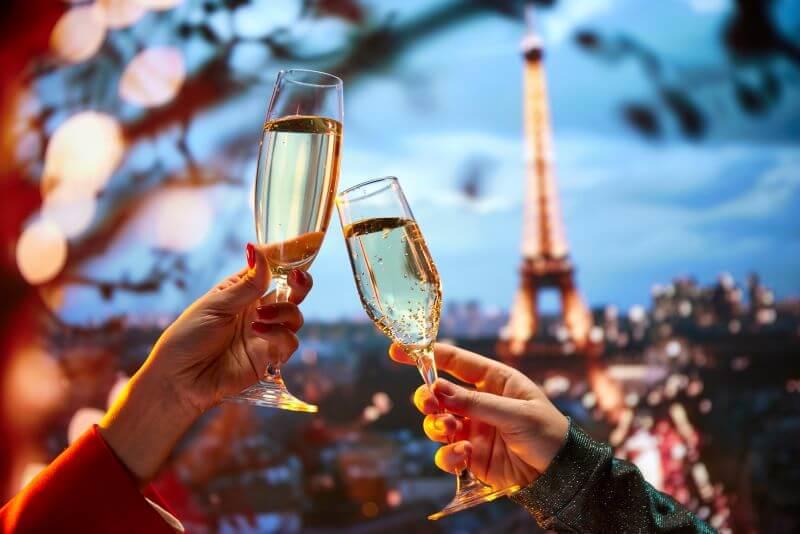 friends toasting champagne glasses in front of the Eiffel Tower at night