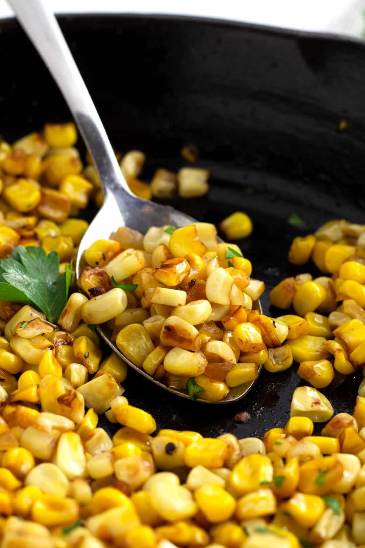 Close-up of roasted corn kernels in a pan, slightly charred and golden, ready to be added to chili