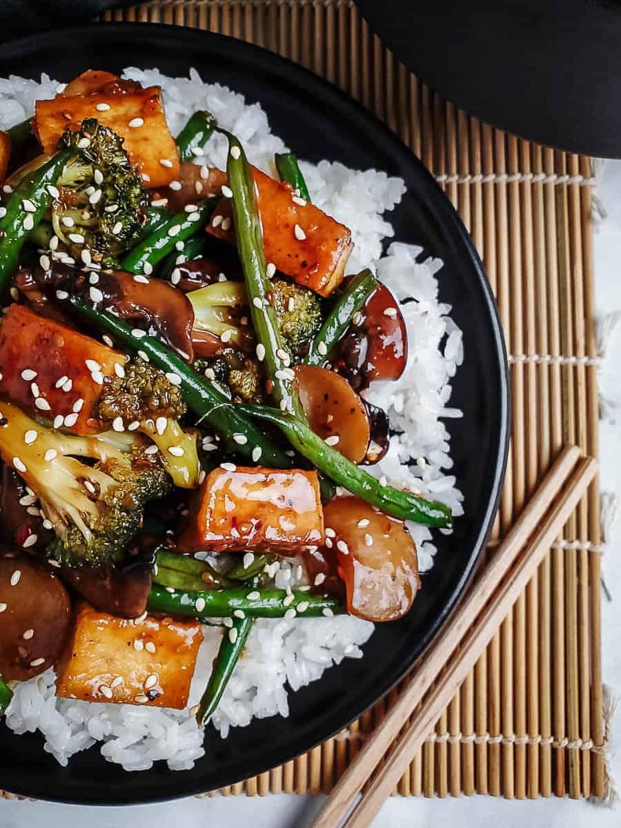 a beautifully plated Teriyaki Tofu Tower Stir-Fry on a dark wooden table