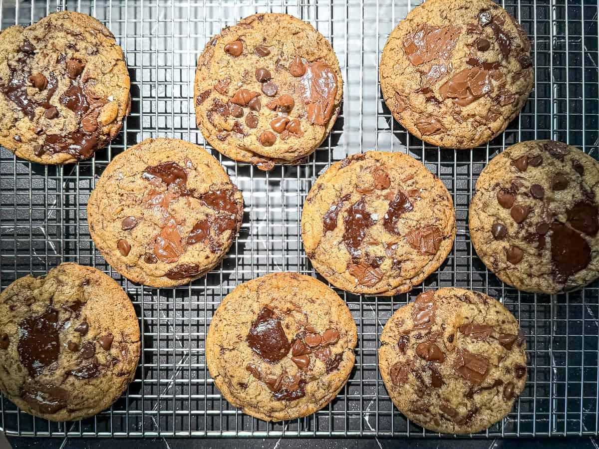 Close-up of a freshly baked triple-chip cookie slab, showing melted chocolate and golden edges, cooling on a wire rack