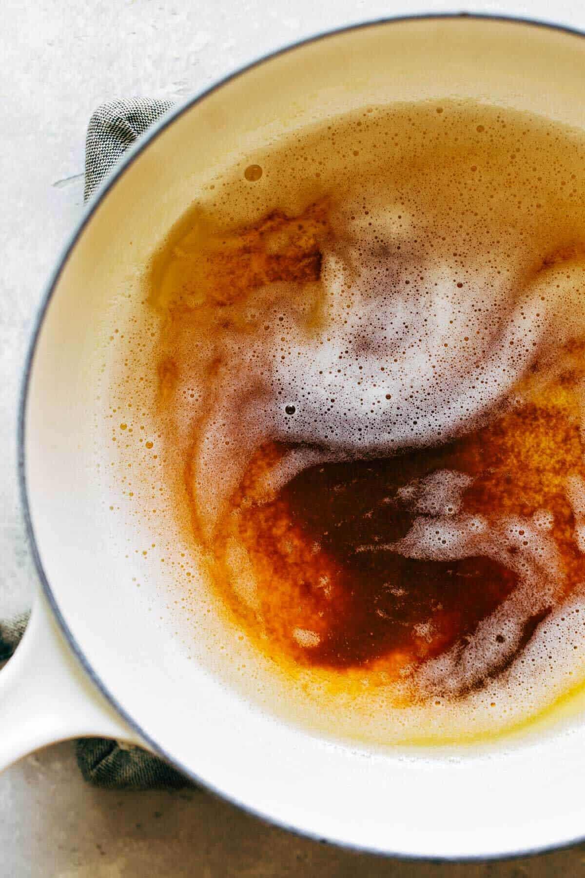 Brown butter bubbling in a small saucepan, turning golden with specks