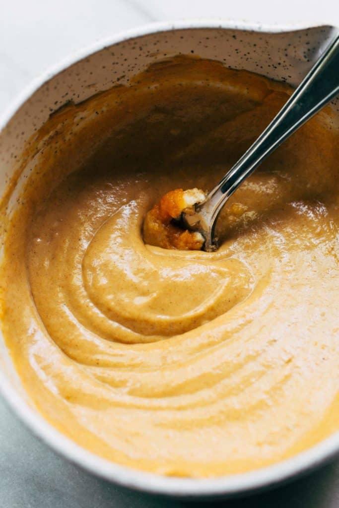 close-up of hands mixing pumpkin pie filling in a bowl