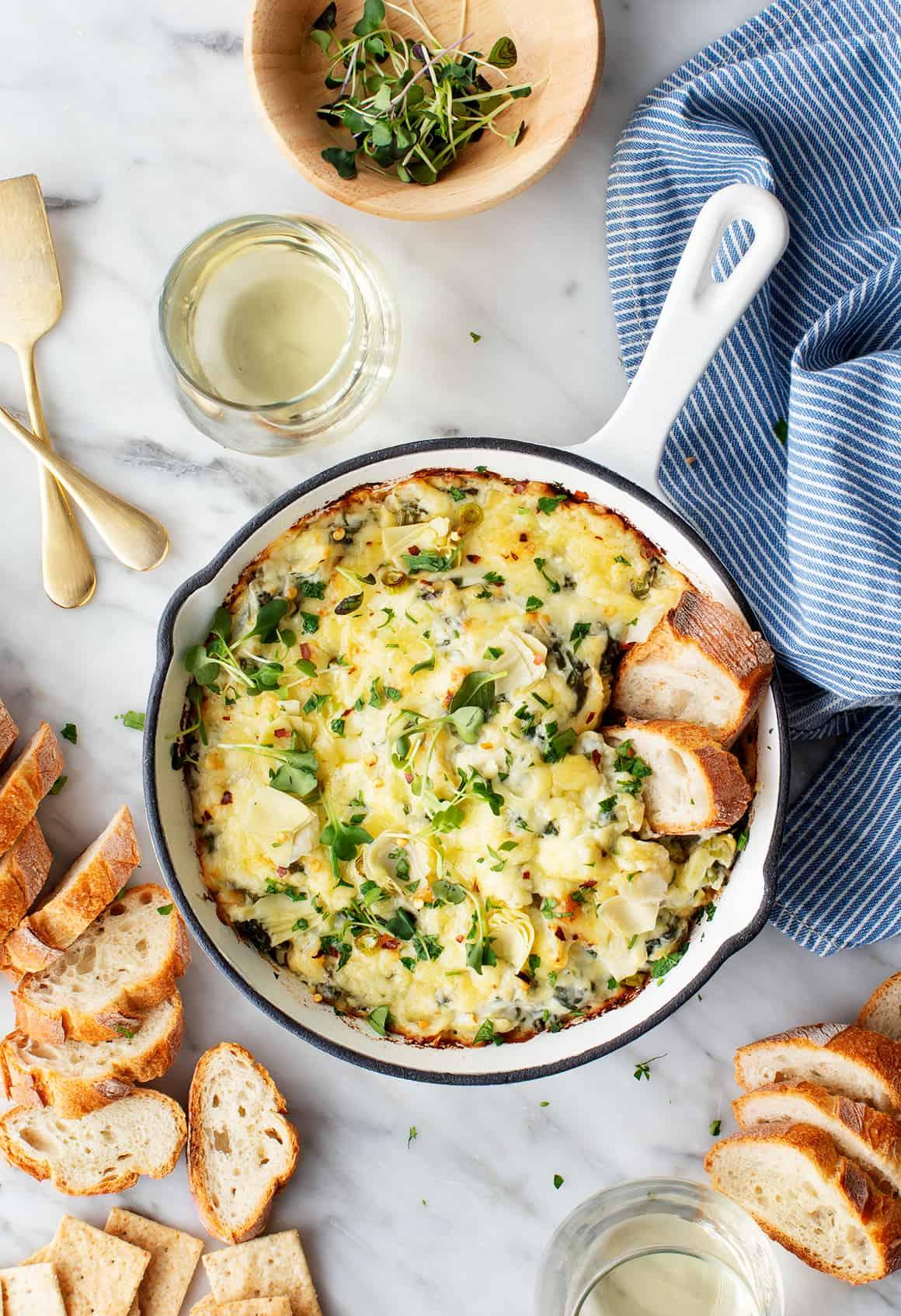 Serving spoon scooping creamy spinach artichoke dip into a small bowl, garnished with parsley