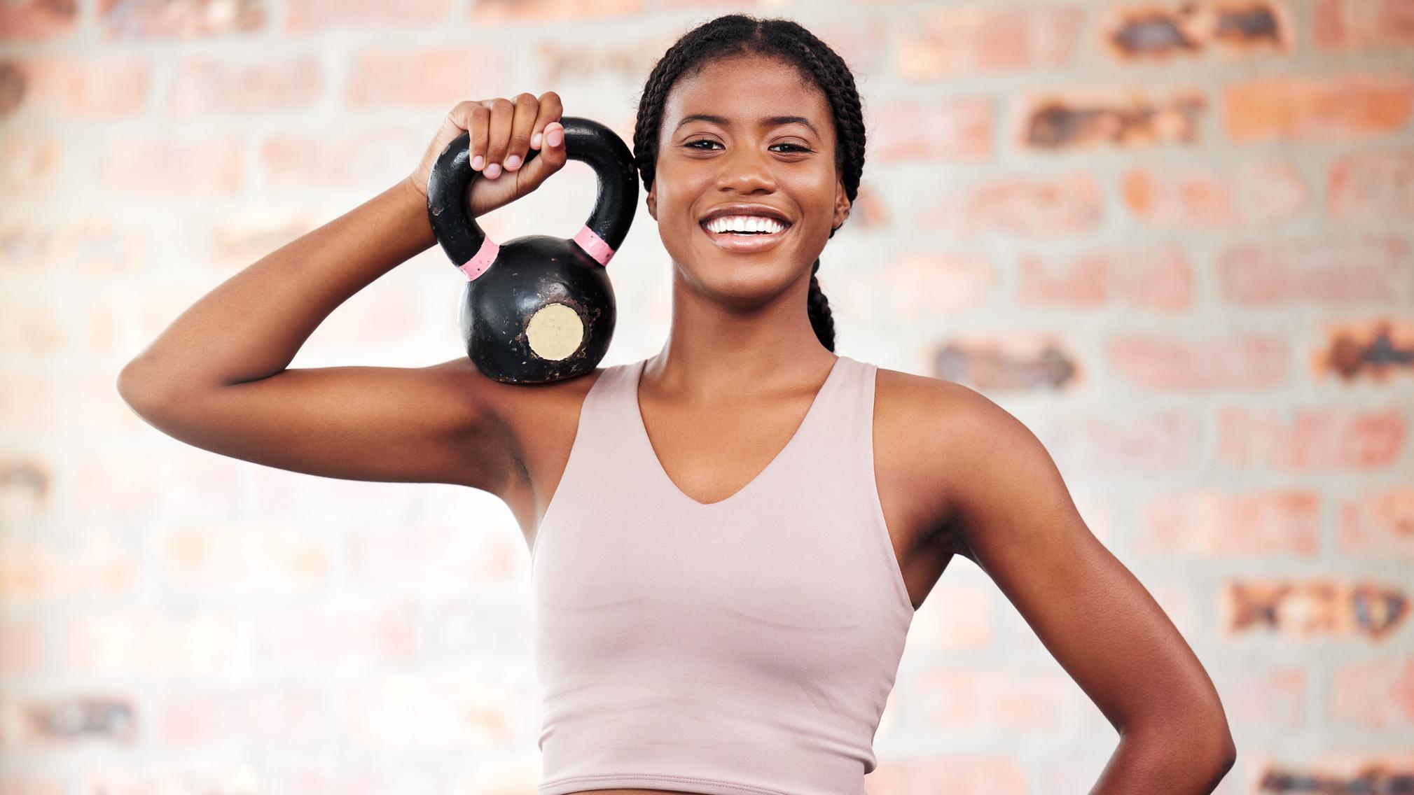 woman smiling and doing both dumbbell and kettlebell exercises