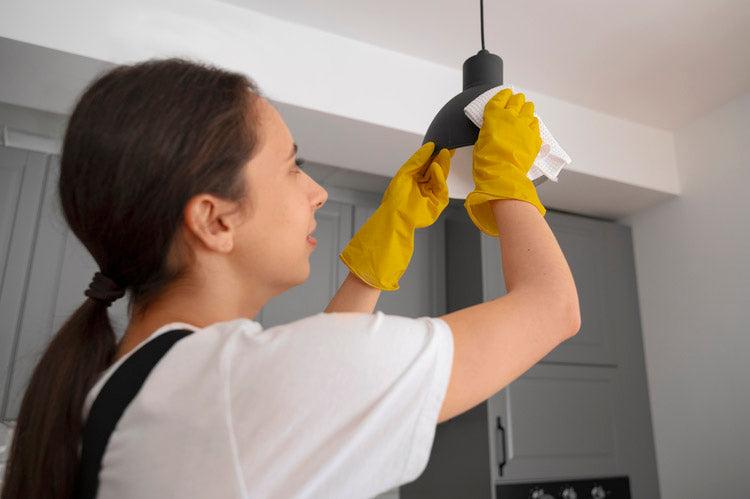 woman cleaning light fixture in a home