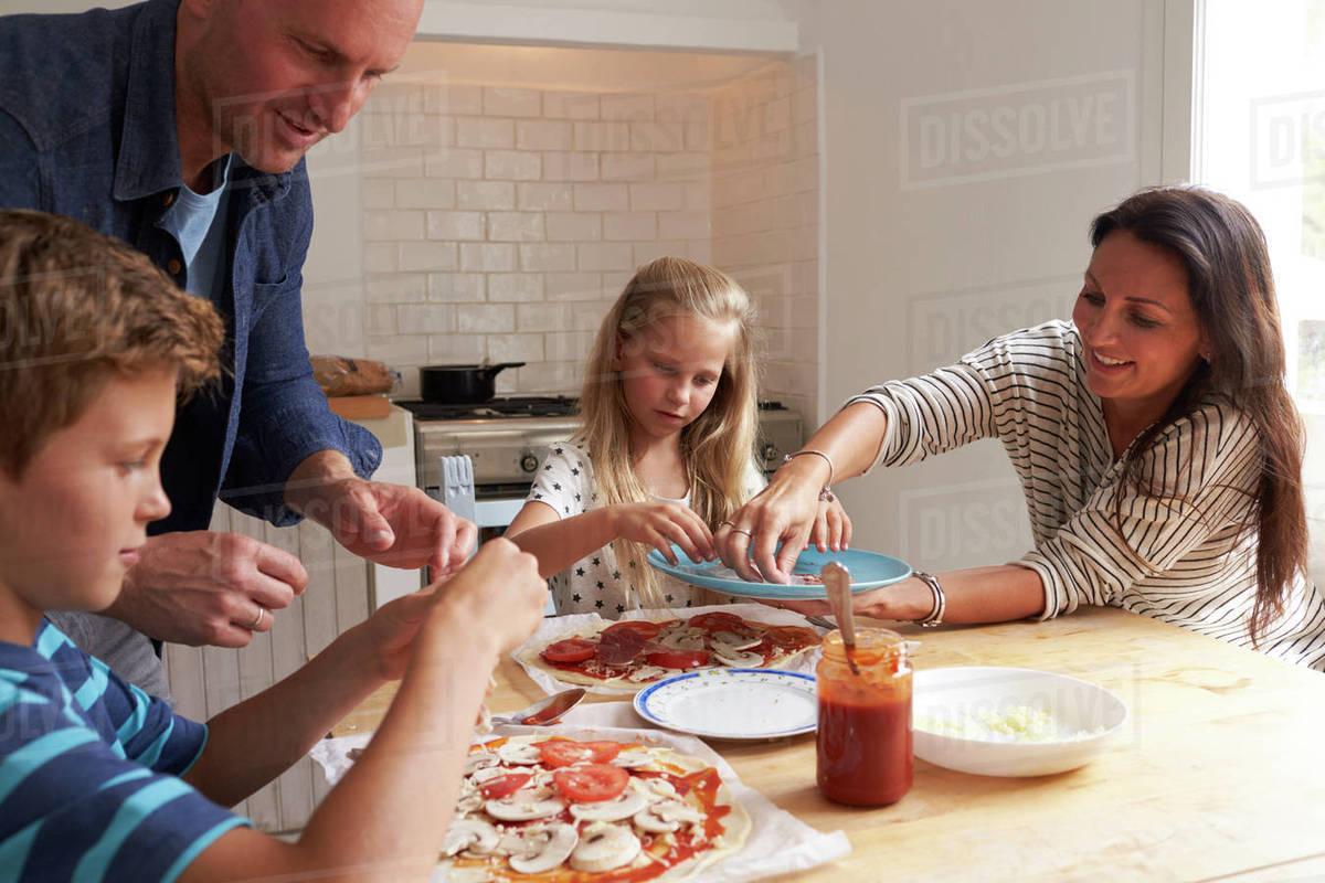 Family making pizza rolls together in kitchen