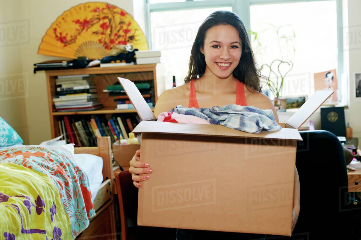 happy student unpacking in college dorm room