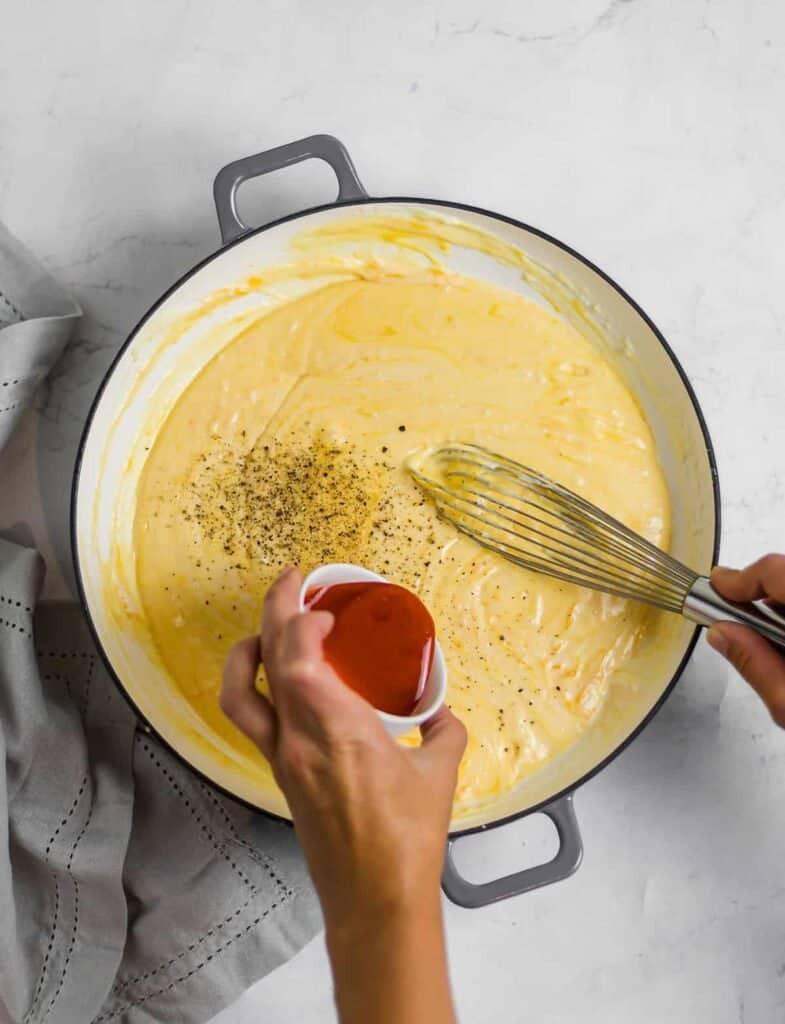 pouring cheese sauce over macaroni
