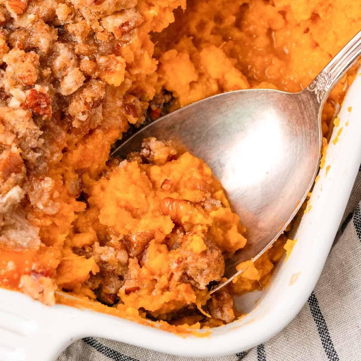 close-up of a spoonful of sweet potato casserole showing creamy texture and golden maple butter, steam rising