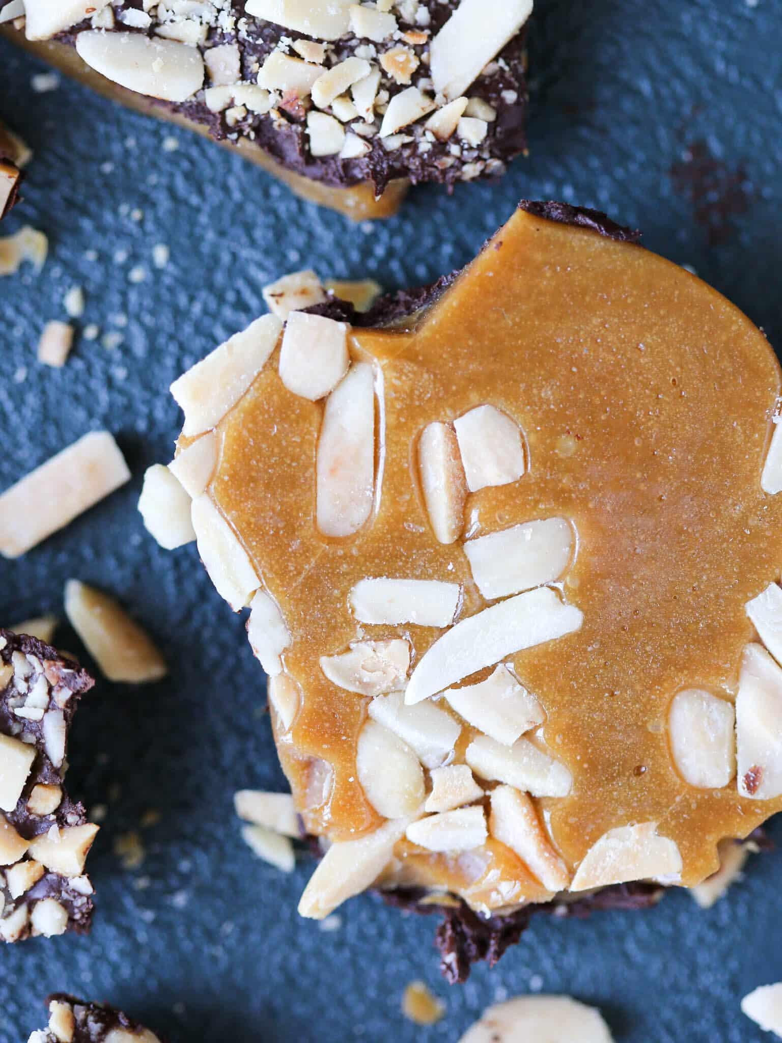 Close-up of glossy melted toffee being poured onto parchment paper with almonds