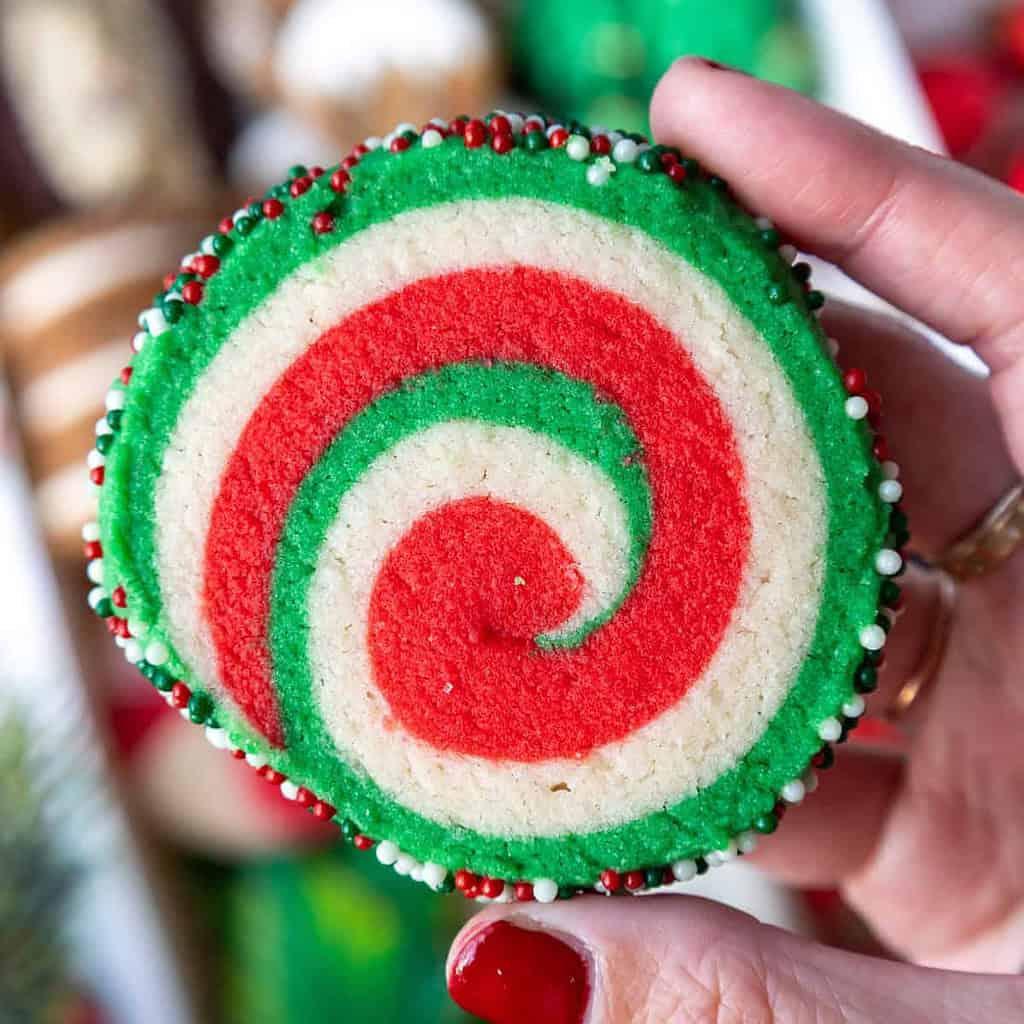 Hands gently pressing two different colored cookie doughs together to create a swirl pattern