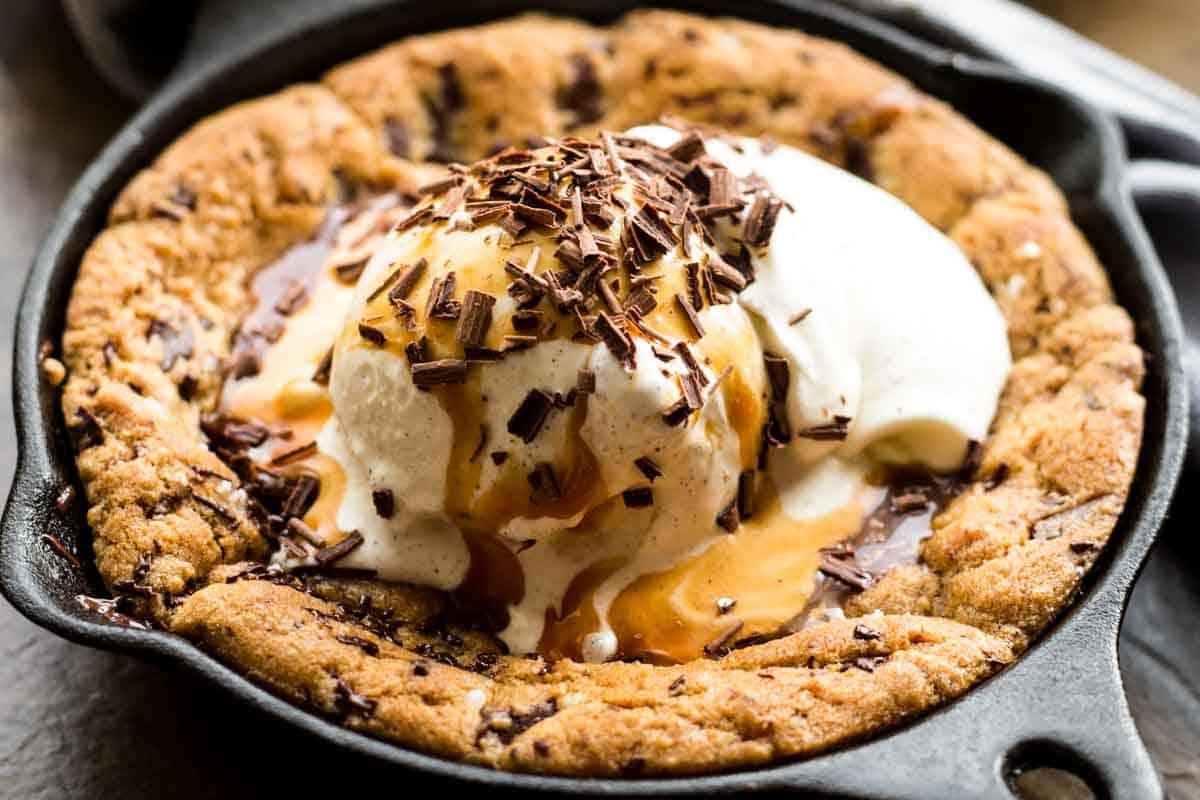 Close-up of a gooey cookie wedge with melted chocolate, on a plate with vanilla ice cream
