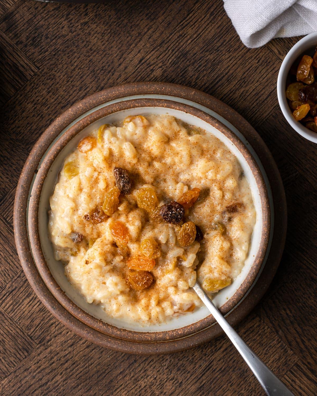 Warm baked rice pudding with a creamy top, golden brown, served in a rustic bowl with a spoon