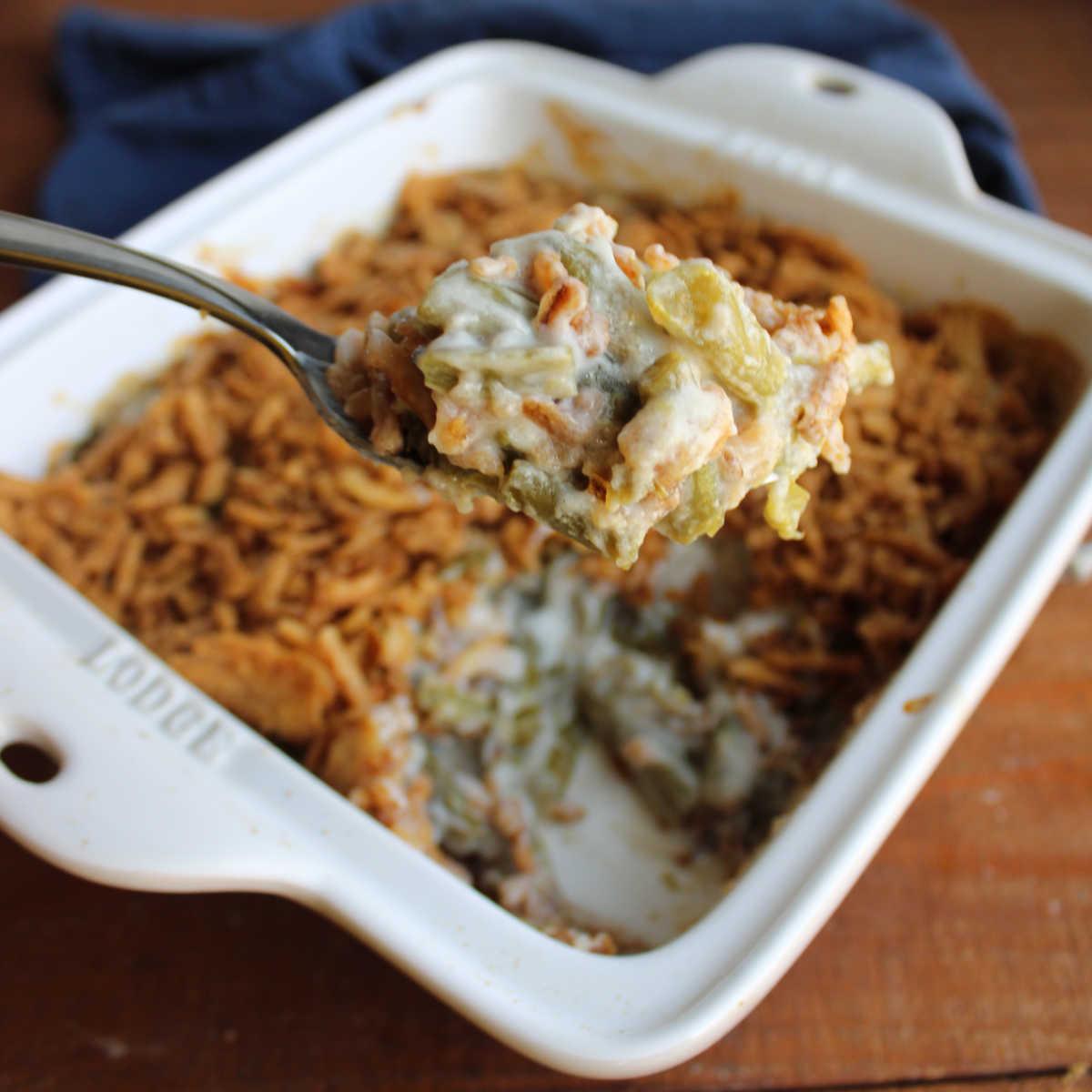 Serving spoon scooping green bean parmesan bake from a casserole dish