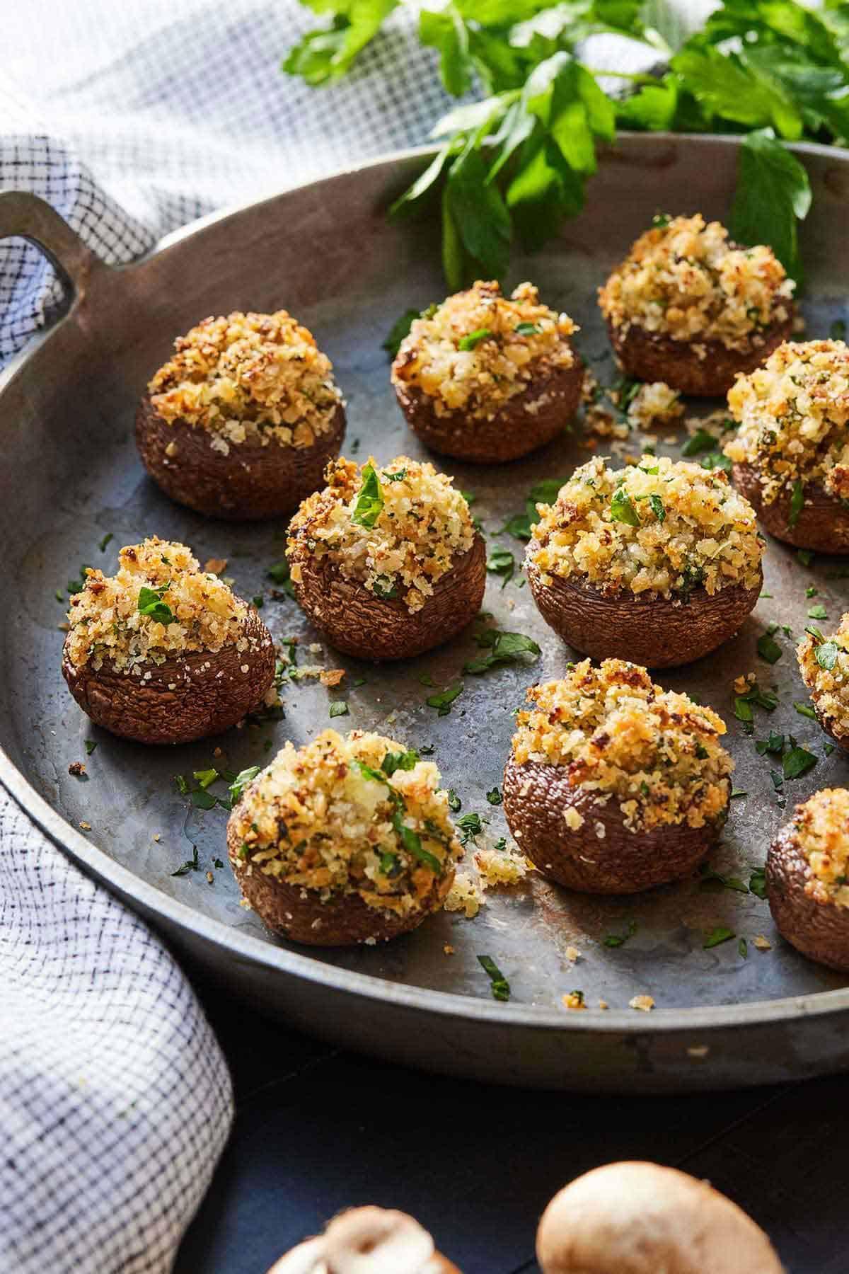 A close-up of a rustic wooden bowl filled with a vibrant mixture of chopped mushroom stems, minced garlic, fresh parsley, thyme, breadcrumbs, and grated Parmesan cheese, ready for stuffing
