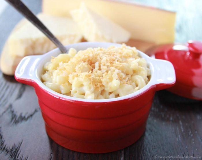 Cozy shot of a bowl of truffle mac and cheese next to a fireplace with soft lighting