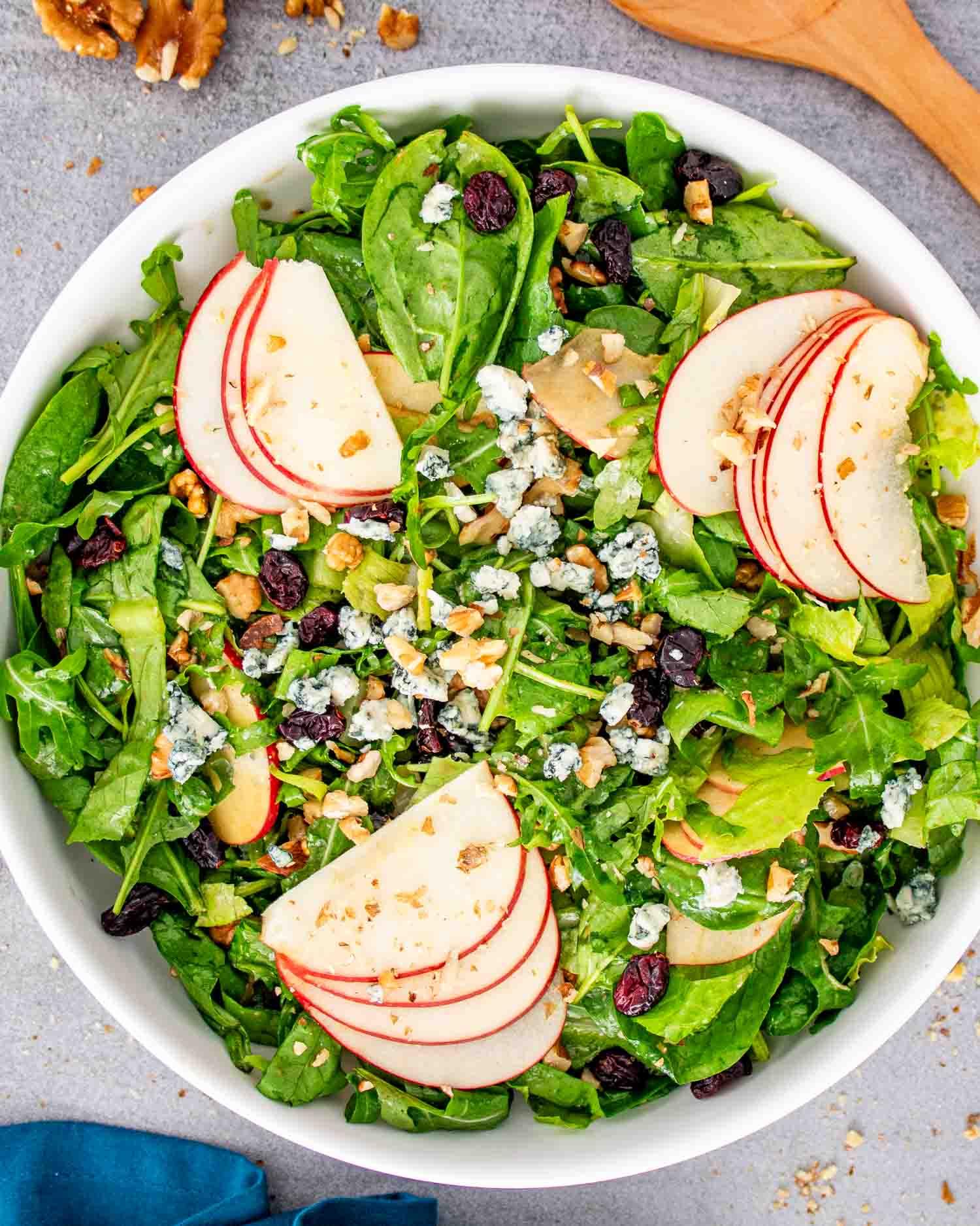 Bowl of mixed greens with apples and walnuts, pre-dressing