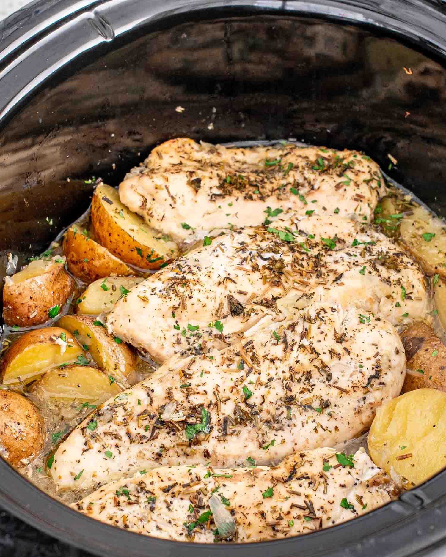 family gathered around a table with crockpot chicken and potatoes