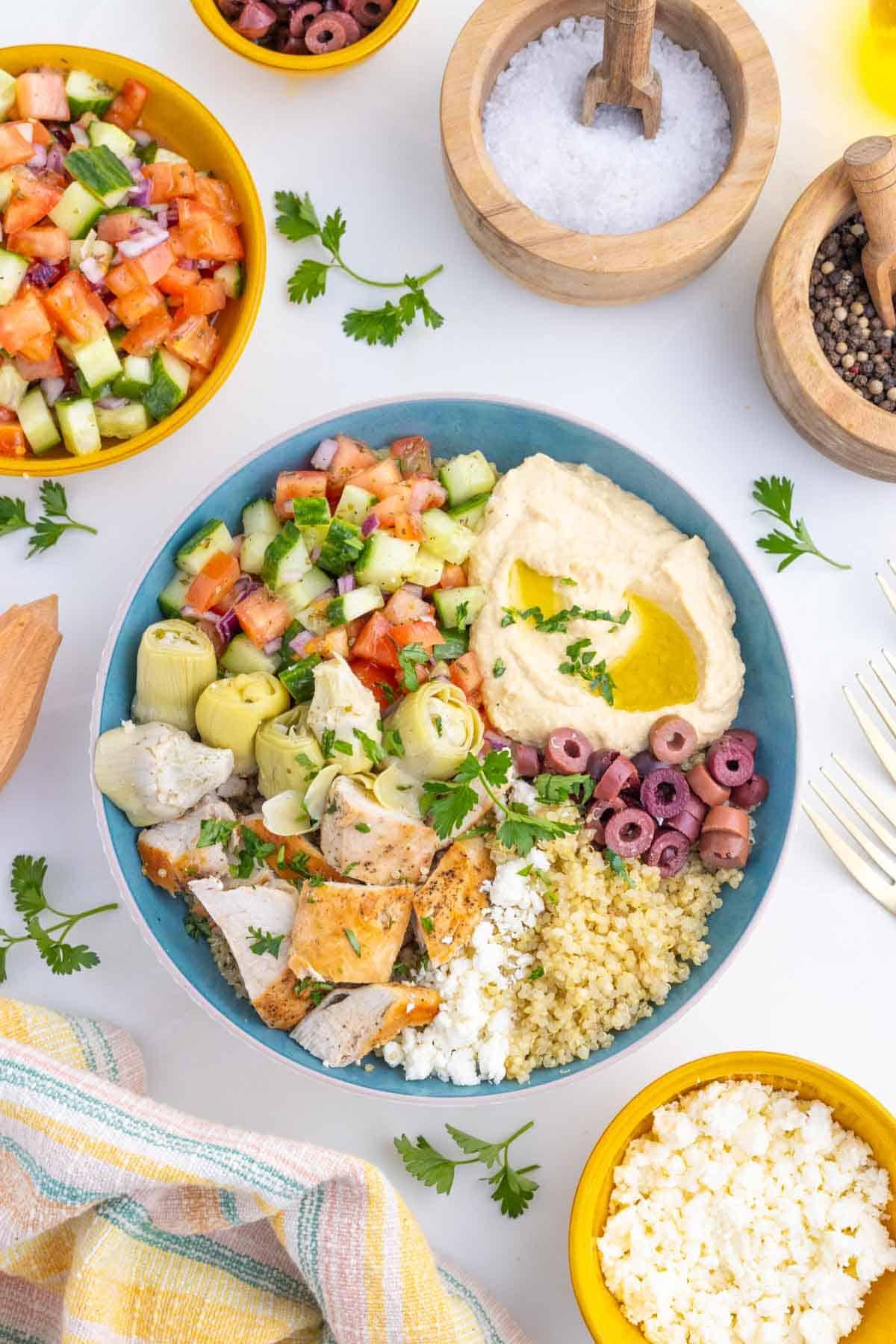 Overhead shot of a colorful Greek chicken bowl with tzatziki, olives, and fresh vegetables