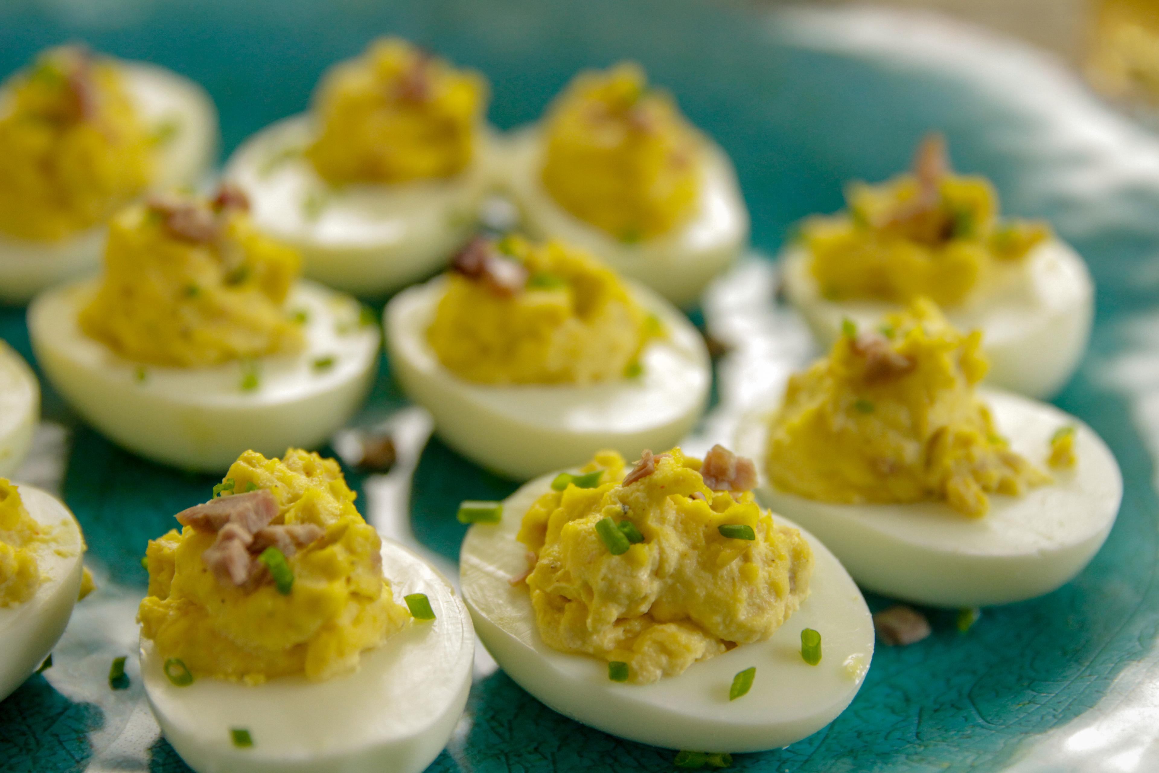 Lively outdoor summer barbecue scene with a vintage platter of deviled eggs in focus, sun shining