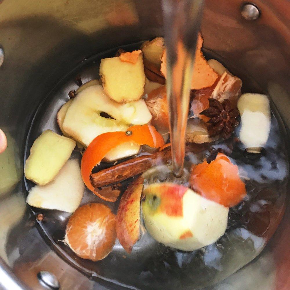 A person adding a pinch of cinnamon to a simmering pot of soup