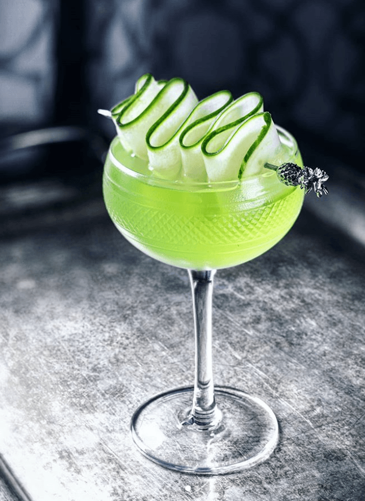 close-up shot of muddling cucumber and melon in a highball glass