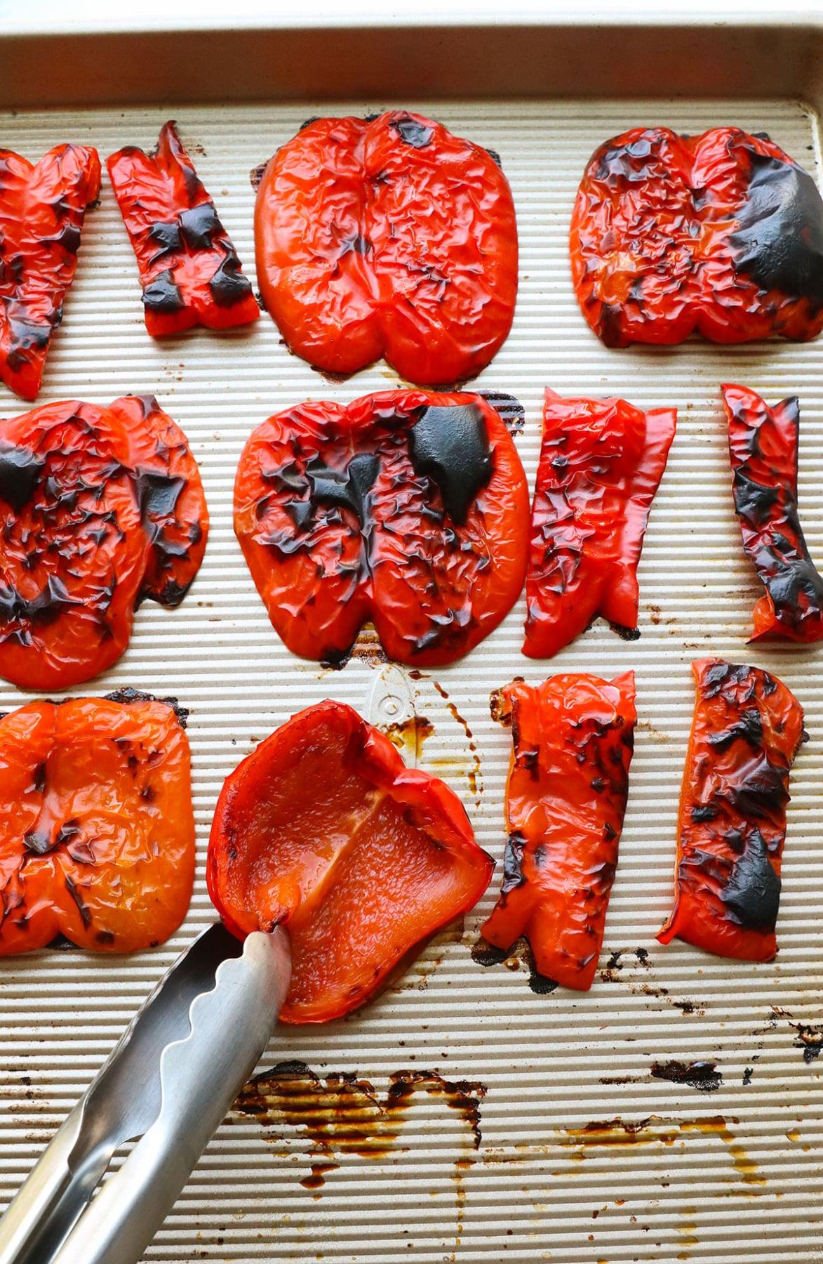 bright red bell peppers roasting on a baking sheet
