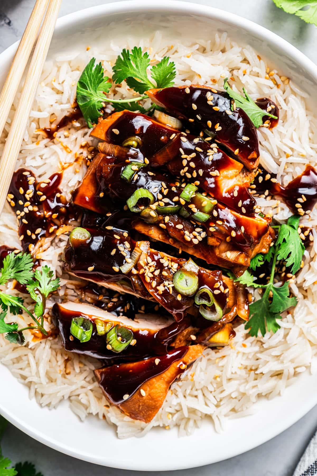 vibrant sticky teriyaki chicken with sesame seeds and green onions on rice, close-up, natural light