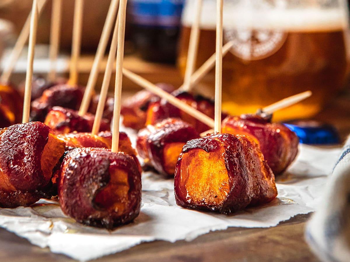 bacon-wrapped sweet potato appetizers being arranged on a serving dish