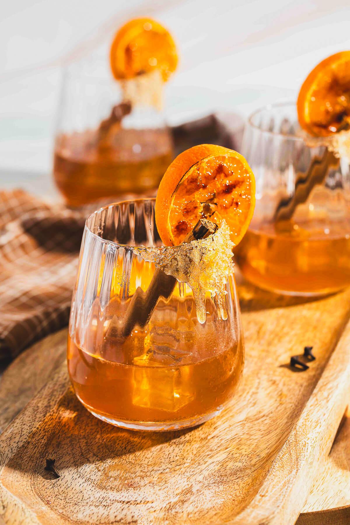 garnished glass of orange clove punch with cinnamon stick and orange slice