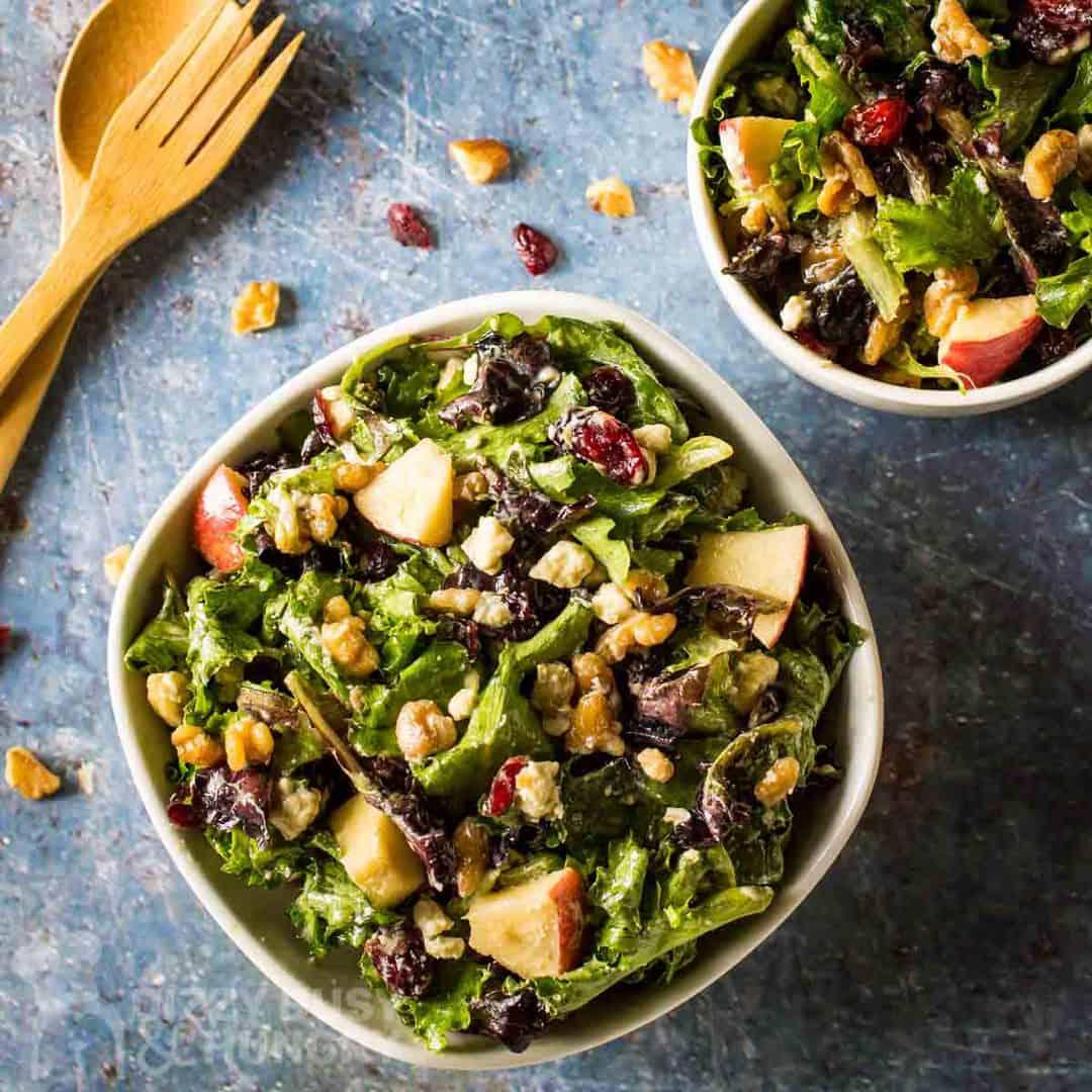 Overhead shot of a fresh apple walnut salad being tossed