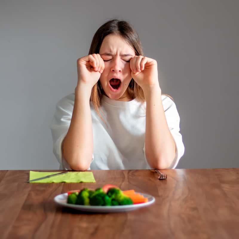 person looking tired but happy eating a healthy avocado dinner