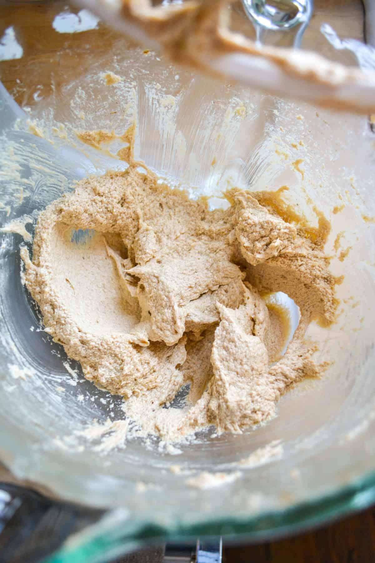 Close up of vanilla bean paste being added to cookie dough in a mixing bowl